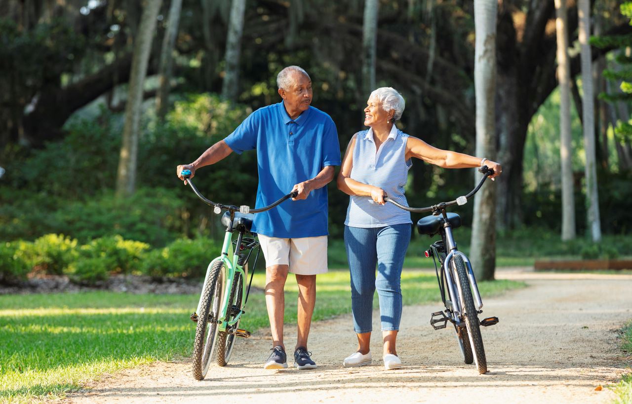 Older couple walking with bikes on trail